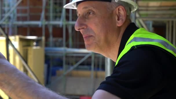 男性建筑工人工头 测量师 工人或建筑师站在建筑工地上 站在脚手架上与同事交谈和挥手 — 图库视频影像