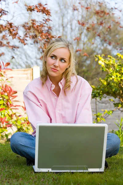 Задумчивая девушка молодая женщина использует ноутбук компьютер в своем саду у себя дома — стоковое фото