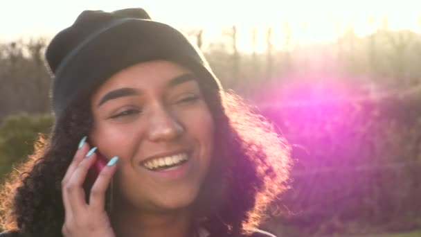 아름다운 인종인 아프리카 미국인 소녀검은 모자를 휴대폰으로 얘기하는 햇살에 백라이트 — 비디오