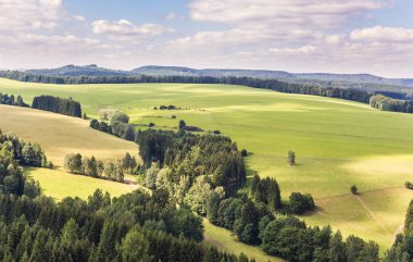Yeşil çayırlar ve tepelerde büyüyen ağaçlar ile kırsal manzara. Gökyüzü ve bulutlar ile manzara.