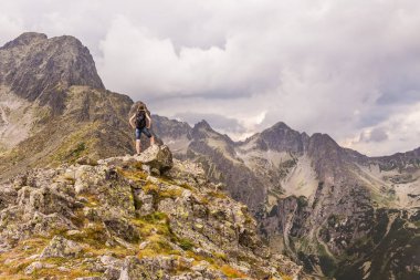 Kara bulutlar ile ağır dağ manzarası. Zirve tırmandıktan sonra dağ panorama gözlemleyerek bir kadın. Yüksek Tatras Slovakya.