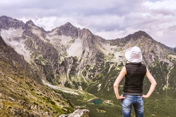 A woman at the top of the mountain, admiring mountain scenery. Tatra mountains landscape from the summit.