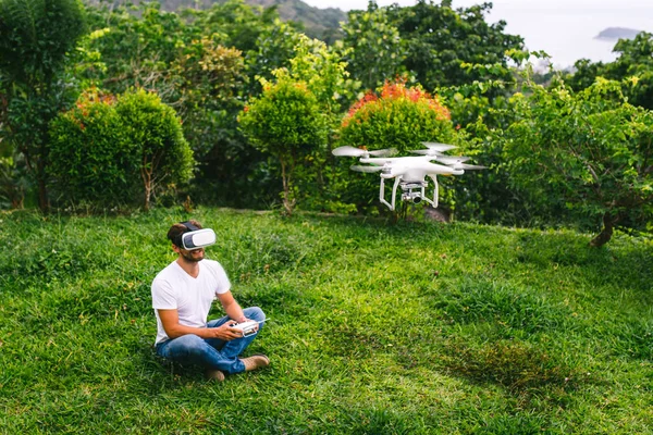 Um homem com um capacete de realidade virtual sentado ao lado do drone — Fotografia de Stock