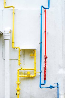 Beyaz bir duvar üzerinde renkli su boruları. Sarı. Kırmızı. Mavi