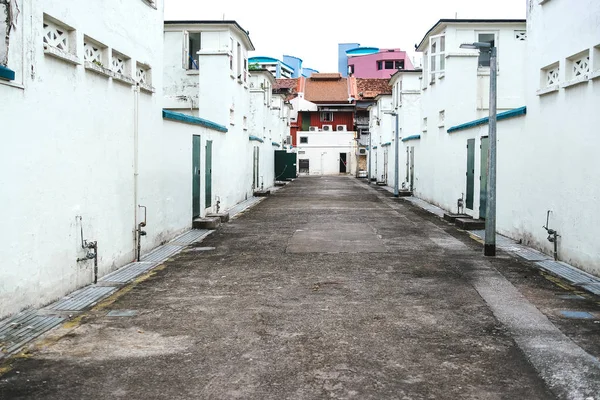 The old deserted street in Asia. The concrete road. White shabby wall