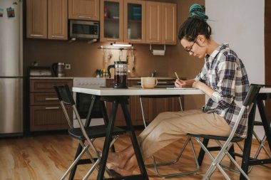 Mutfakta, yemek masasında çalışan bir kadın. Rahat bir pozisyonda. Karantina.