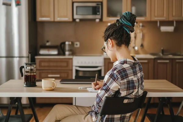 A woman keeps notes in a notebook while working at home. Quarantine, self-isolation.