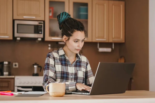 A woman keeps notes in a notebook at a remote job at home. Work from home.