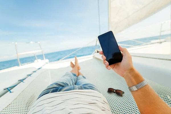 Phone in the hand of a vacationer on a yacht. Keep in touch during your vacation. speed Internet. Watch content on your phone. Roaming in other countries.