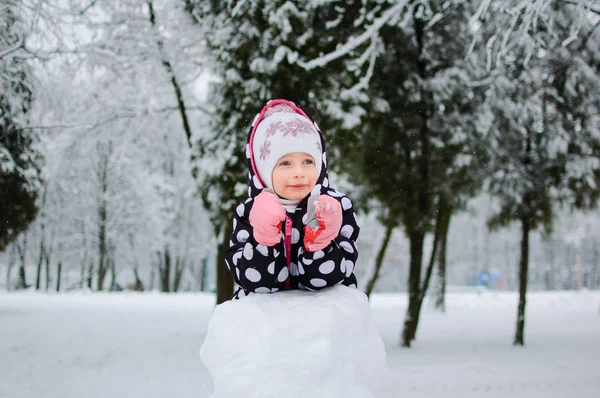 A little girl sitting on snow in winter park — Stock Photo, Image