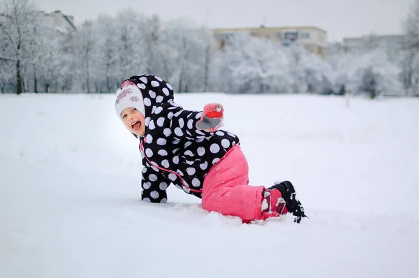 冬の公園で雪の上に座っている少女 — ストック写真
