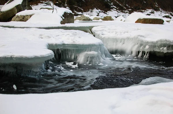 El río de la montaña corre rápidamente bajo una gruesa corteza de hielo . — Foto de Stock