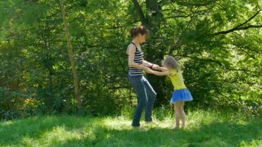 Sıcak güneşli parkta birlikte zevk etkin mutlu bir aile. Kızı kendini çevresinde dönen genç esmer anne.