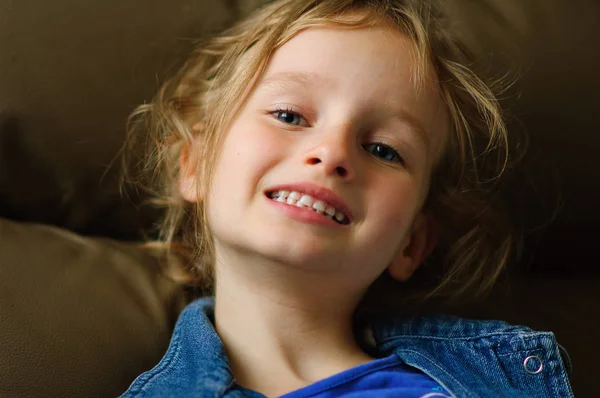 Portrét kudrnaté modrooké děvče s důvěřivým úsměvem. Ona ukazuje zuby mléčné. — Stock fotografie