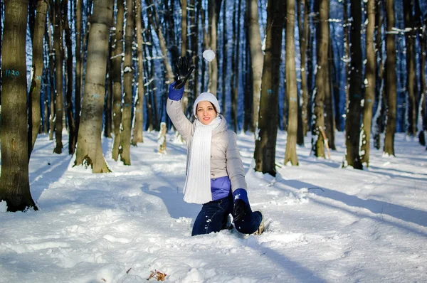 Mladá žena hází sněhovou hraje v zasněžené parku za slunečného počasí v zimě. — Stock fotografie