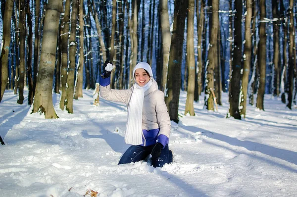 Attiva ragazza sta lanciando una palla di neve che gioca all'aperto nel parco innevato durante un tempo soleggiato in inverno . — Foto Stock