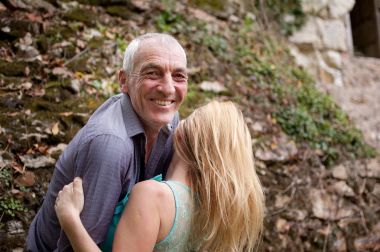 Handsome Senior Man Hugging His Young Girlfriend Outdoors and Smiling Looking at the Camera. clipart