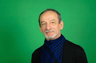 Siyah kazak ve mavi etmek eşarp çevresinde Well-trimmed sakallı adam onun boyun seyir Studio yeşil zemin üzerine kameraya gri saçlı kıdemli