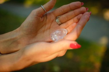 Vumfit, imbuilding veya meditasyon için şeffaf ametist kuvars yoni yumurta ile Kadın el. Gökyüzü ve gündoğumu arka plan açık havada ellerde parlayan kristal yumurta. Kadın sağlığı kavramı.