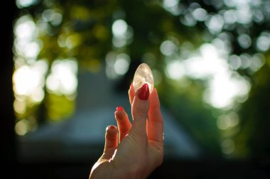 Vumfit, imbuilding veya meditasyon için şeffaf ametist kuvars yoni yumurta ile Kadın el. Gökyüzü ve gündoğumu arka plan açık havada ellerde parlayan kristal yumurta. Kadın sağlığı kavramı.