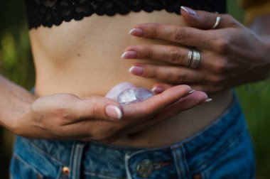 Vumfit, imbuilding veya meditasyon için iki yoni yumurtası tutan kadın eller çıplak karnının üzerinde pembe kuvarstan ve şeffaf mor ametistten yapılır.
