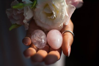 Vumfit, imbuilding veya meditasyon için iki yoni yumurta tutan kadın eller pembe kuvars ve beyaz çiçekler kapalı şeffaf menekşe ametist yapılır