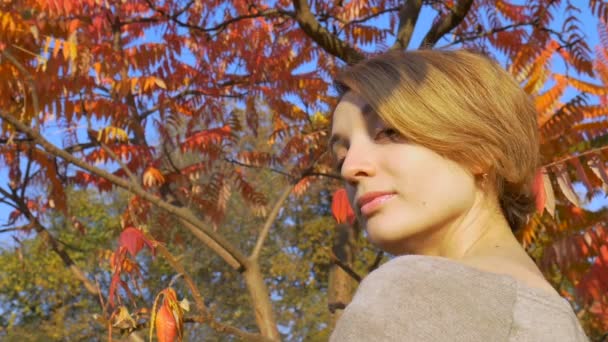 Chica joven con el pelo corto y rubio está sosteniendo un cepillo de dientes de bambú al aire libre durante el clima soleado en otoño sobre fondo de hojas rojas y naranjas. Adecuación al medio ambiente y concepto cero residuos — Vídeos de Stock