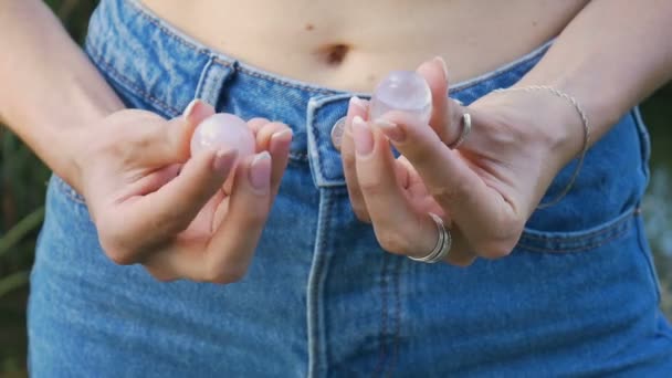 Mano femminile che tiene in mano un quarzo rosa e uova di yoni di cristallo ametista. Salute delle donne, unità con i concetti di natura. Chiudi il ritratto di una ragazza non identificabile in jeans a stomaco nudo — Video Stock