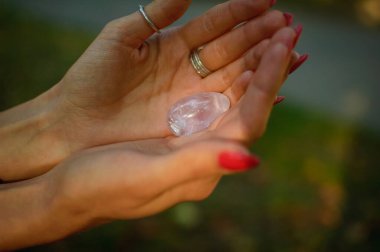 Vumfit, imbuilding veya meditasyon için şeffaf ametist kuvars yoni yumurta ile Kadın el. Gökyüzü ve gündoğumu arka plan açık havada ellerde parlayan kristal yumurta. Kadın sağlığı kavramı.