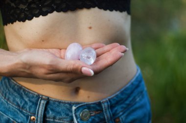 Vumfit, imbuilding veya meditasyon için iki yoni yumurtası tutan kadın eller çıplak karnının üzerinde pembe kuvarstan ve şeffaf mor ametistten yapılır.