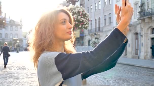 Vrouwelijk buitenshuis portret van een vrouw toerist het nemen van een foto vroeg in de ochtend op het plein in de oude Europese stad tijdens zonsopgang — Stockvideo