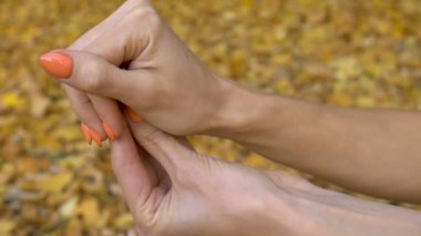 Turuncu manikürlü kadın eli, sonbahar günü açık havada düşen sarı yapraklar üzerinde vumfit, imbuilding veya meditasyon için şeffaf menekşe ametist yoni yumurtası tutuyor.