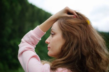 Pembe elbiseli, yeşil orman geçmişi olan, bahar ya da sonbahar başlarında dağlarda dolaşan pembe saçlı genç, sakin bir kadının yan görüntüsü. Tatil ya da tatil kavramı