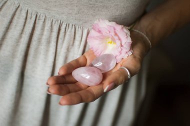 Vumfit, imbuilding veya meditasyon için iki yoni yumurta tutan kadın eller pembe kuvars ve beyaz çiçekler kapalı şeffaf menekşe ametist yapılır