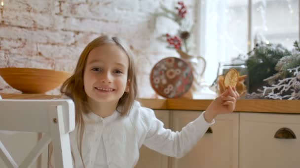 Улыбающаяся маленькая блондинка закрывает глаза сушеными цитрусовыми ломтиками дома с мансардой и рождественским декором, счастливая детская концепция — стоковое видео