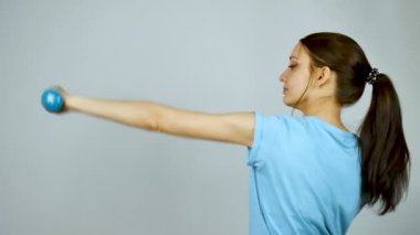 Gri Stüdyo Arkaplanda Egzersiz Yapan Elde Ahmak Güzel Genç Spor Kadını. Spor kıyafetli at kuyruklu güzel kız. Vücut Geliştirme Konsepti.
