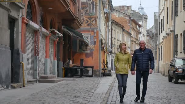 早春または秋の間に古代都市の屋外を歩く年齢差の幸せなロマンチックなカップルの肖像画. — ストック動画