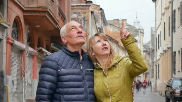 Ritratto di coppia romantica felice con differenza di età che abbraccia e indica qualcosa all'aperto nella città antica all'inizio della primavera o dell'autunno . — Video Stock