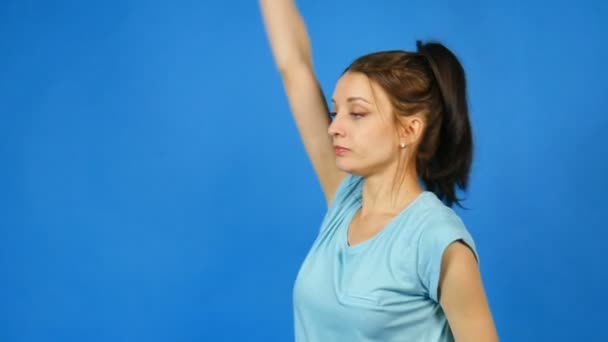 Pretty Young Sports Woman with Dumbbell in Hand Making Her Exercise at Blue Studio Background (en inglés). Chica bonita con cola de caballo en Fitwear. Concepto de culturismo . — Vídeos de Stock