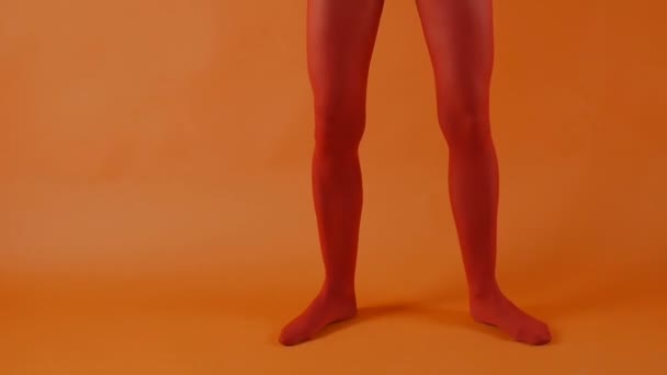 Röda strumpor på perfekt kvinna ben över ljusa orange bakgrund, kvinnlig modell dansar i studio — Stockvideo