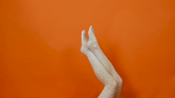 Bas résille blanc sur les jambes de femme parfaites sur fond orange vif en studio — Video