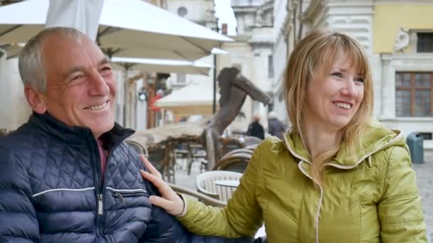 Hombre mayor guapo está abrazando a su joven esposa rubia pasar tiempo juntos al aire libre en la ciudad antigua durante principios de primavera u otoño . — Vídeos de Stock