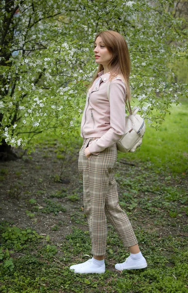 Foto in piena altezza di donna bionda in abiti casual in giardino durante l'inizio della primavera accanto all'albero fiorito — Foto Stock