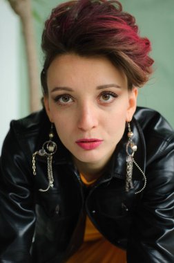 Glam rock tarzı koyu pembe saçlı, mohawk saçlı, sarı elbiseli, siyah deri ceketli, yakın plan kadın portresi olan güzel bir kız.