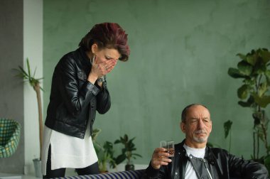 Yetişkin kız, sarhoş yaşlı babası çatı katındaki bir kanepede çiçeklerle oturduğu için ağlıyor. Alkol bağımlılığı, aile kavramlarında alkolik.