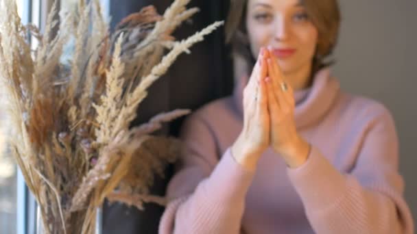 Mãos femininas segurando dois ovos yoni feitos de quartzo rosa e ametista violeta transparente para vumfit, imbuilding ou meditação perto da janela com vaso de espiguetas . — Vídeo de Stock