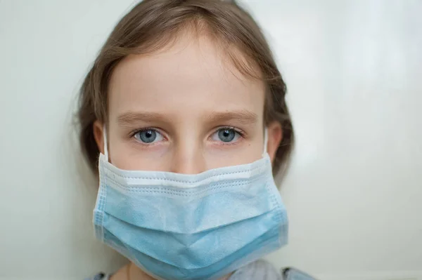 Brote de Coronavirus Covid-19. Niña rubia con ojos azules usando máscara desechable para la protección del virus sobre fondo blanco en el estudio. Concepto de equipo de protección individual — Foto de Stock