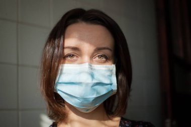 Coronavirus Covid-19 salgını. Pandemia sırasında virüsten korunmak için yüzüne cerrahi maske takan genç bir kadın.