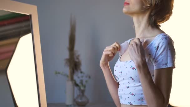 Το κορίτσι κάνει ένα μασάζ gua sha μπροστά από τον καθρέφτη στο σπίτι χρησιμοποιώντας τριαντάφυλλο χαλαζία μασάζ, φυσική πέτρα. Ανύψωση, τόνωση του λεμφικού συστήματος και αντιγηραντική δράση — Αρχείο Βίντεο