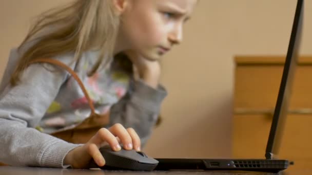 La mano de un niño pequeño sostiene un ratón de computadora en el fondo de la pantalla del ordenador portátil. Educación remota en línea durante la cuarentena y el autoaislamiento durante su estancia en casa — Vídeos de Stock